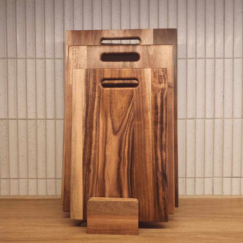 Set of wooden cutting boards with handles against a tiled wall.