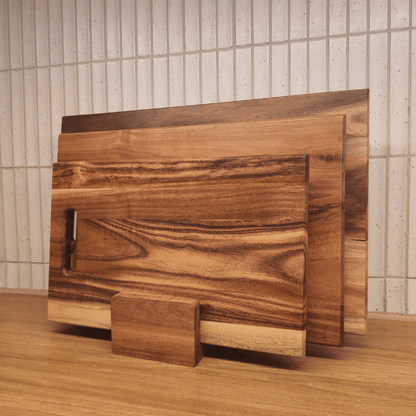 Set of wooden cutting boards on a wooden surface with a tiled wall background
